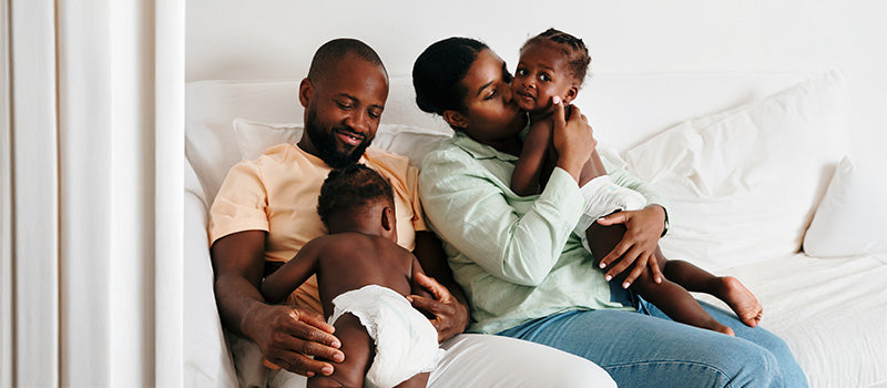 Deux parents sur un canapé avec leurs deux enfants.